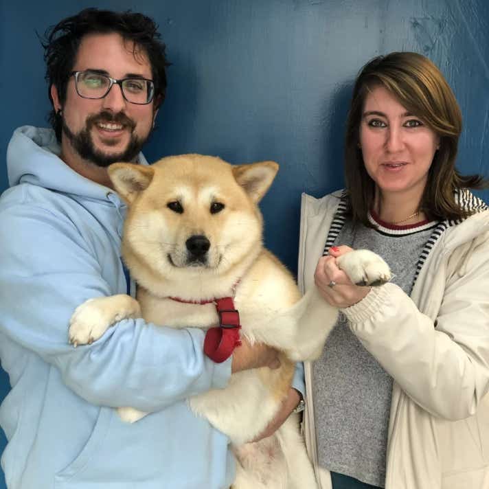 Pareja con un perro shiba inu en brazos en la clínica veterinaria El Jardín.